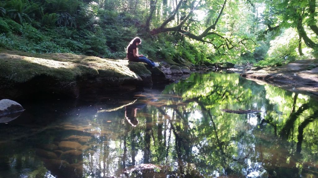 Woodland-creamtion-water Woman sitting by a stream at a woodland burial site
